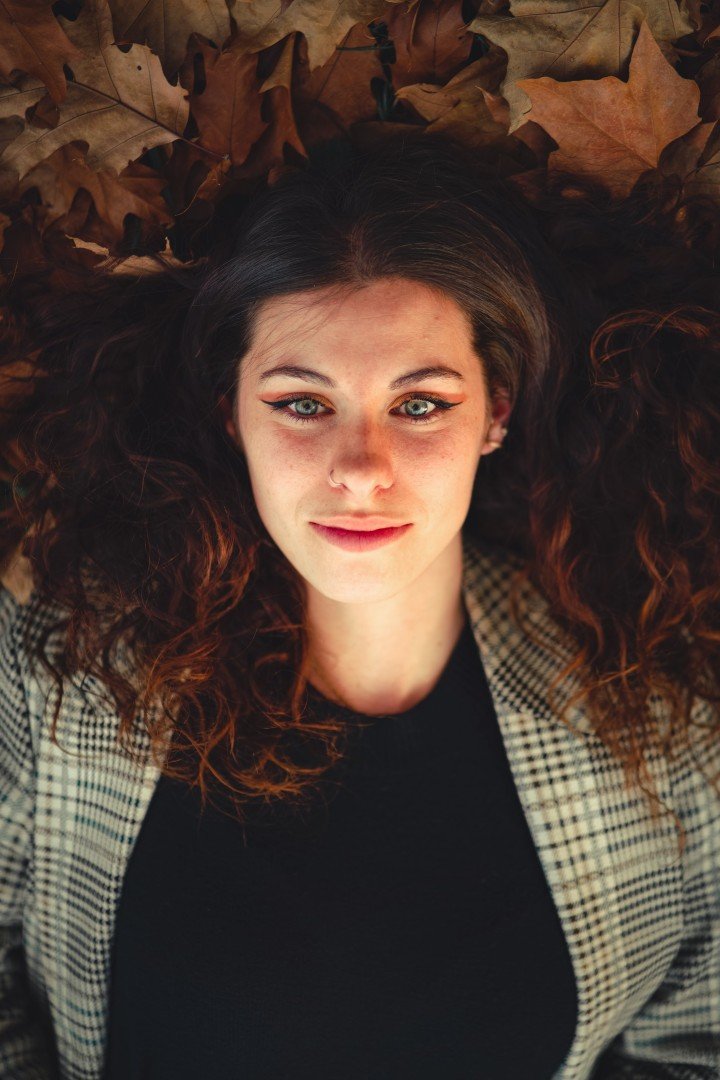 Portrait d’une femme allongée dans un tapis de feuilles mortes